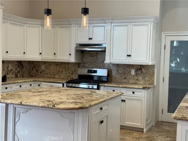 a kitchen with granite countertop white cabinets and a stove