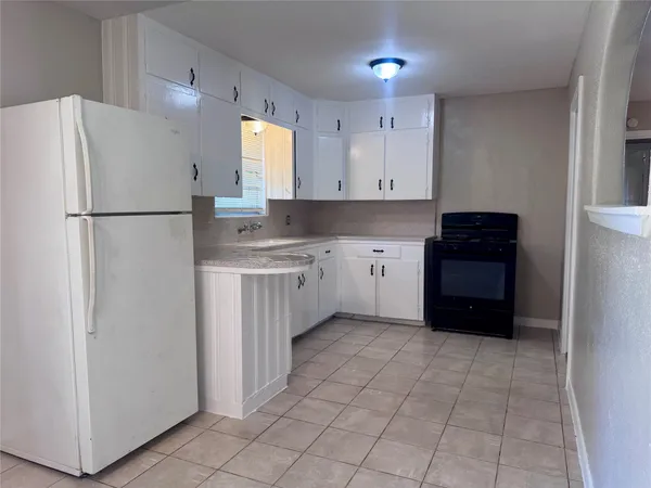 a kitchen with kitchen island granite countertop a sink a refrigerator and a stove