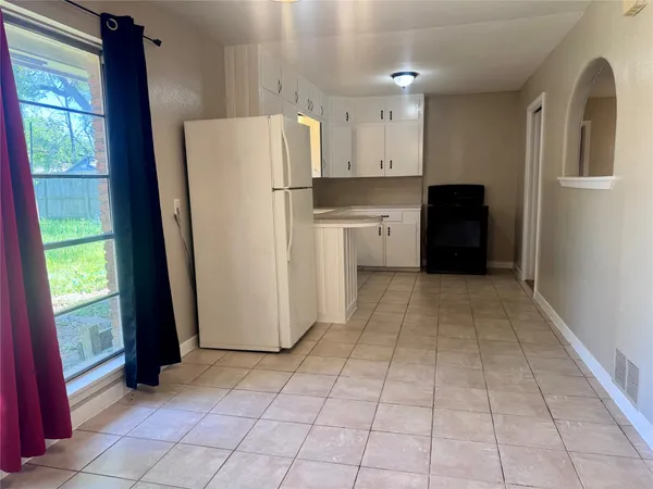 a kitchen with a refrigerator a stove top oven and a window