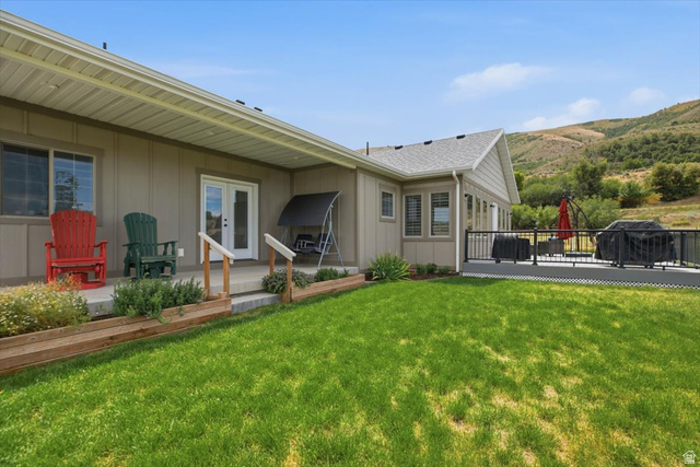 3123 East Riverdale Road Preston, ID 83263 - Photo 29 of 52 Expansive green lawn bordering a covered patio and an elevated deck with black railing