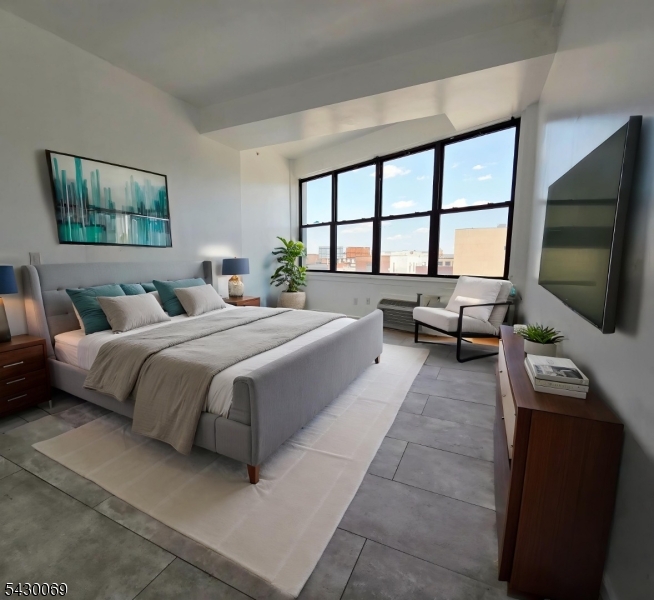30 Howe Avenue, Unit 303 Passaic, NJ 07055 - Photo 4 of 11 a bedroom with a balcony a bed and a flat screen tv