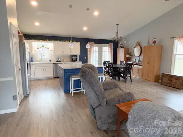 a living room with stainless steel appliances granite countertop furniture wooden floor and a large window