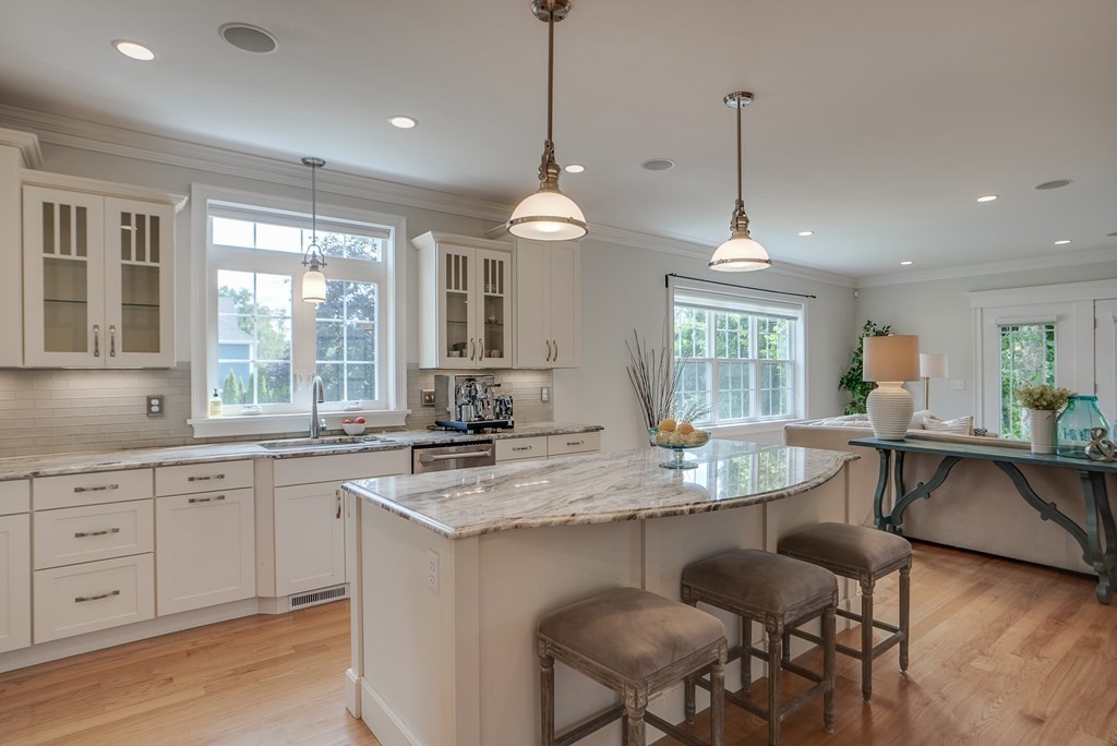 427 Davis Road Bedford, MA 01730 - Photo 3 of 42 a open kitchen with stainless steel appliances granite countertop a stove a sink a center island a dining table and chairs