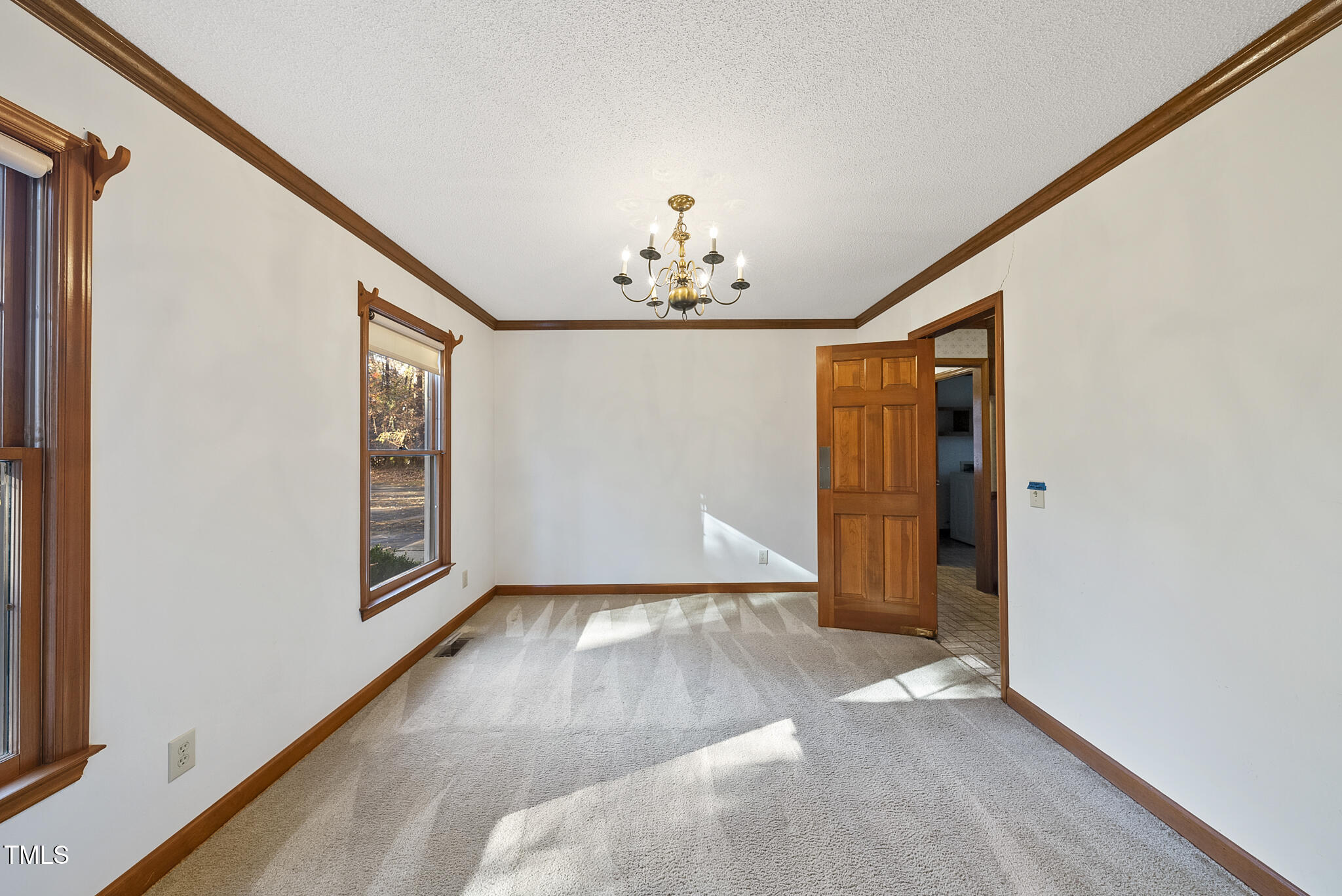 12012 Strickland Road Raleigh, NC 27613 - Photo 18 of 45 an empty room with windows and chandelier