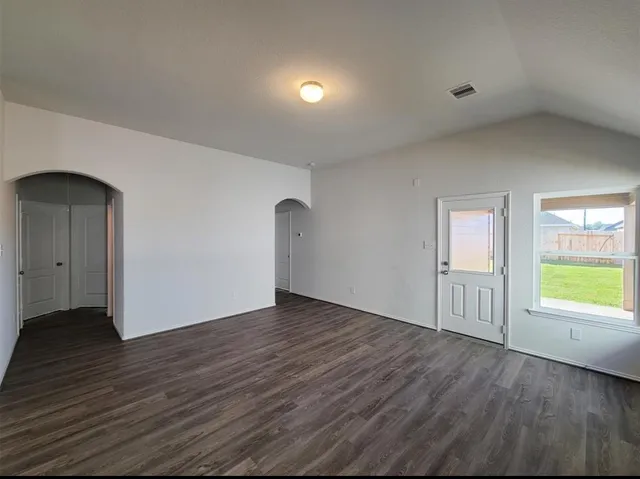 an empty room with wooden floor and windows