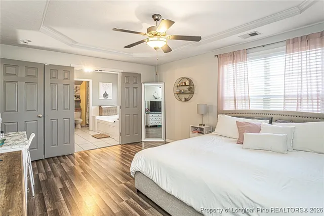 a bedroom with a flat screen tv on dresser and a chandelier