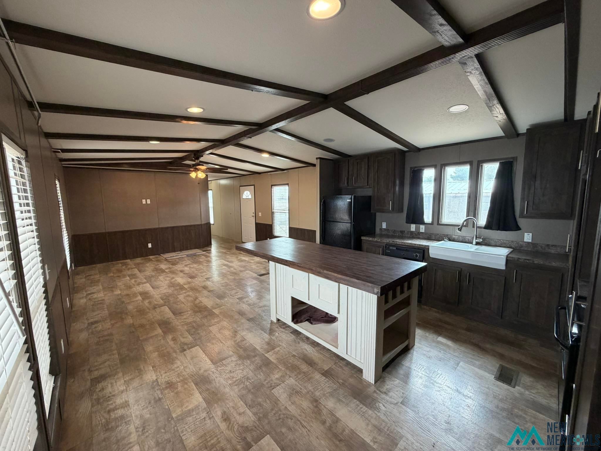 801 Riata Road Carlsbad, NM 88220 - Photo 10 of 39 Open-concept living space featuring wood-finish flooring, exposed ceiling beams, recessed lighting, a ceiling fan, and a kitchen island with a contrasting countertop