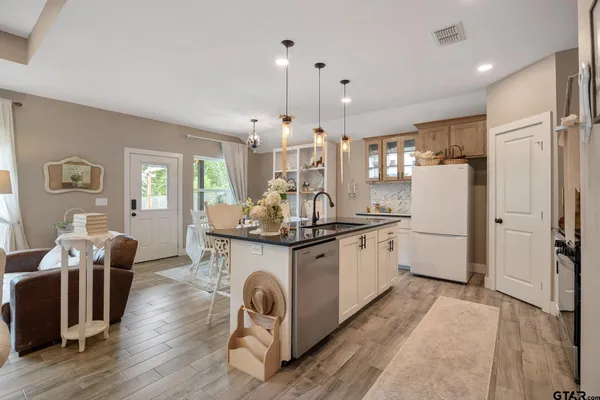 a kitchen with stainless steel appliances granite countertop a refrigerator a stove a sink dishwasher and a dining table with wooden floor