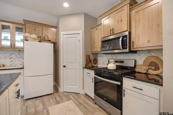 a kitchen with granite countertop a refrigerator stove and white cabinets