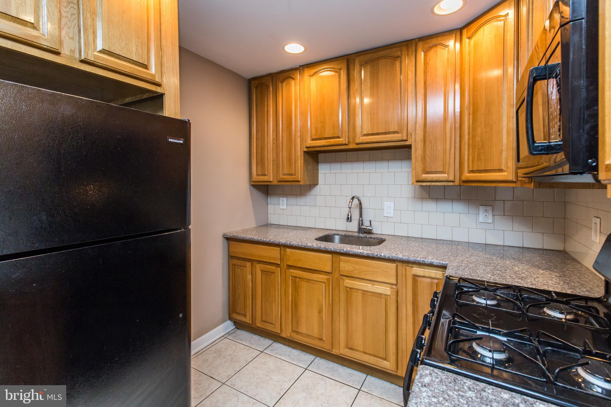 2757 East Country Club Road, Unit 2 Philadelphia, PA 19131 - Photo 8 of 24 a kitchen with a sink a refrigerator and cabinets