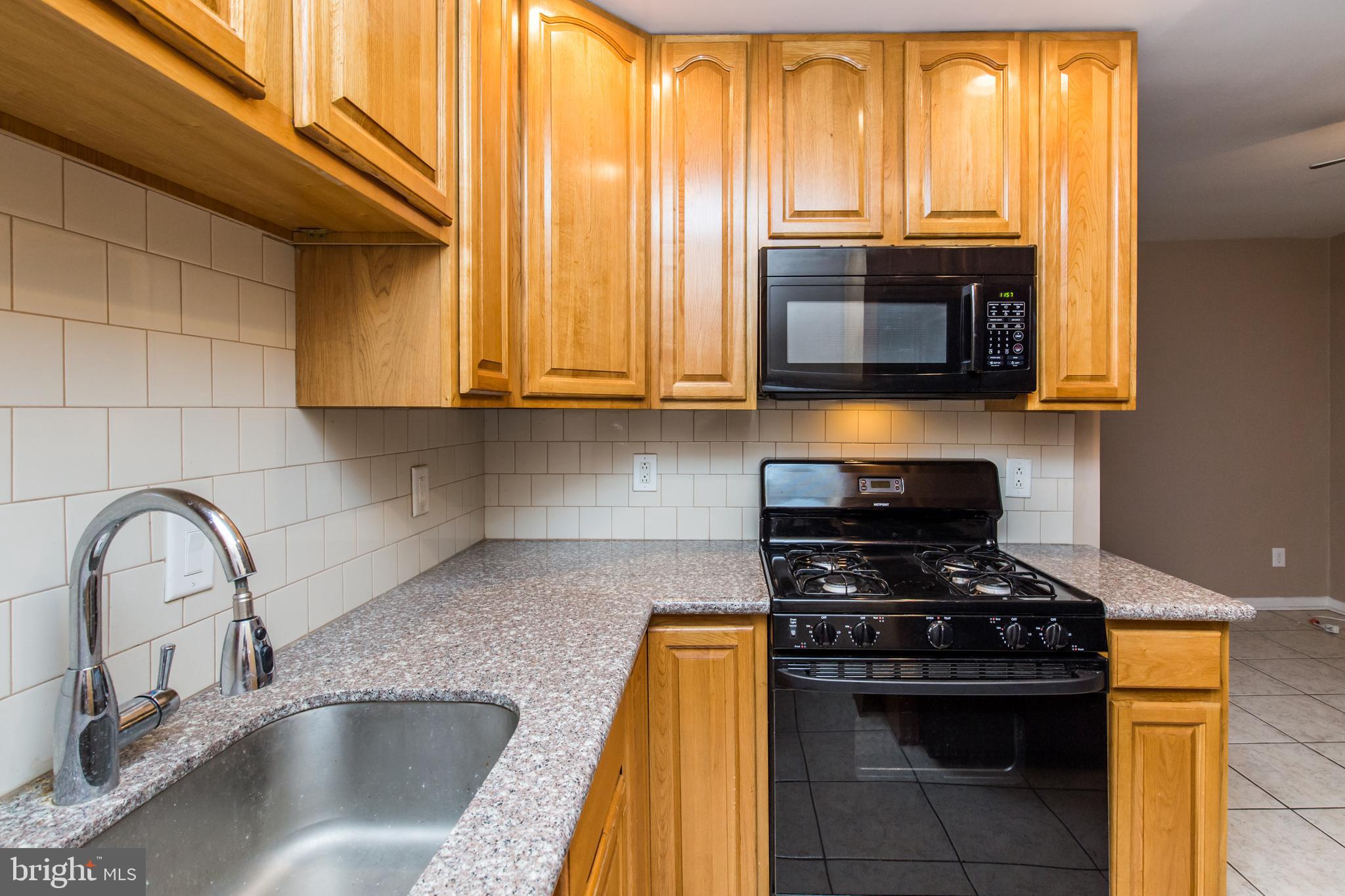 2757 East Country Club Road, Unit 2 Philadelphia, PA 19131 - Photo 9 of 24 a kitchen with granite countertop a stove a sink and a microwave
