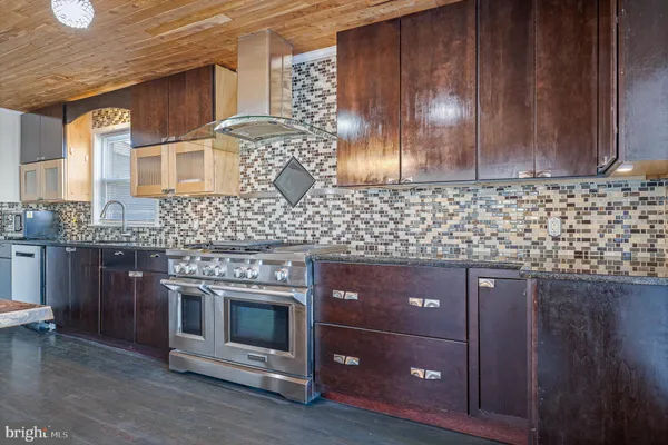 a kitchen with stainless steel appliances granite countertop a stove a sink dishwasher a microwave oven and a dining table with wooden floor