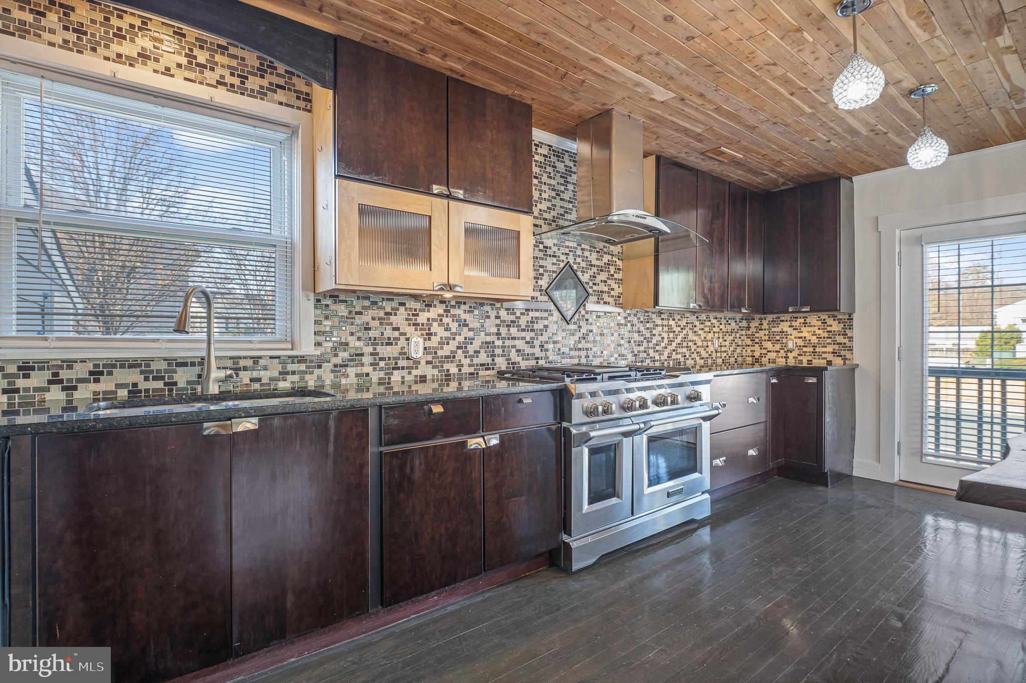 312 North Hammonds Ferry Road Linthicum Heights, MD 21090 - Photo 19 of 56 a kitchen with stainless steel appliances granite countertop a stove a sink dishwasher a microwave oven and a dining table with wooden floor