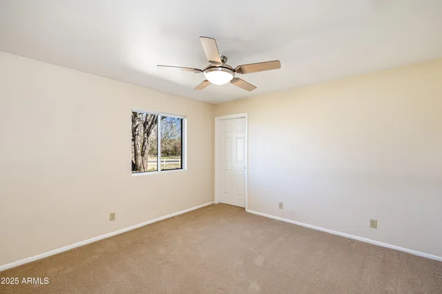 an empty room with windows and fan