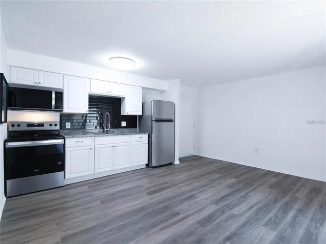 a kitchen with granite countertop a refrigerator and a stove top oven