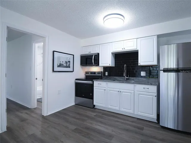 a kitchen with granite countertop a refrigerator stove and microwave