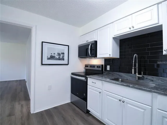 a kitchen with stainless steel appliances granite countertop a sink a stove a microwave a sink and wooden floor