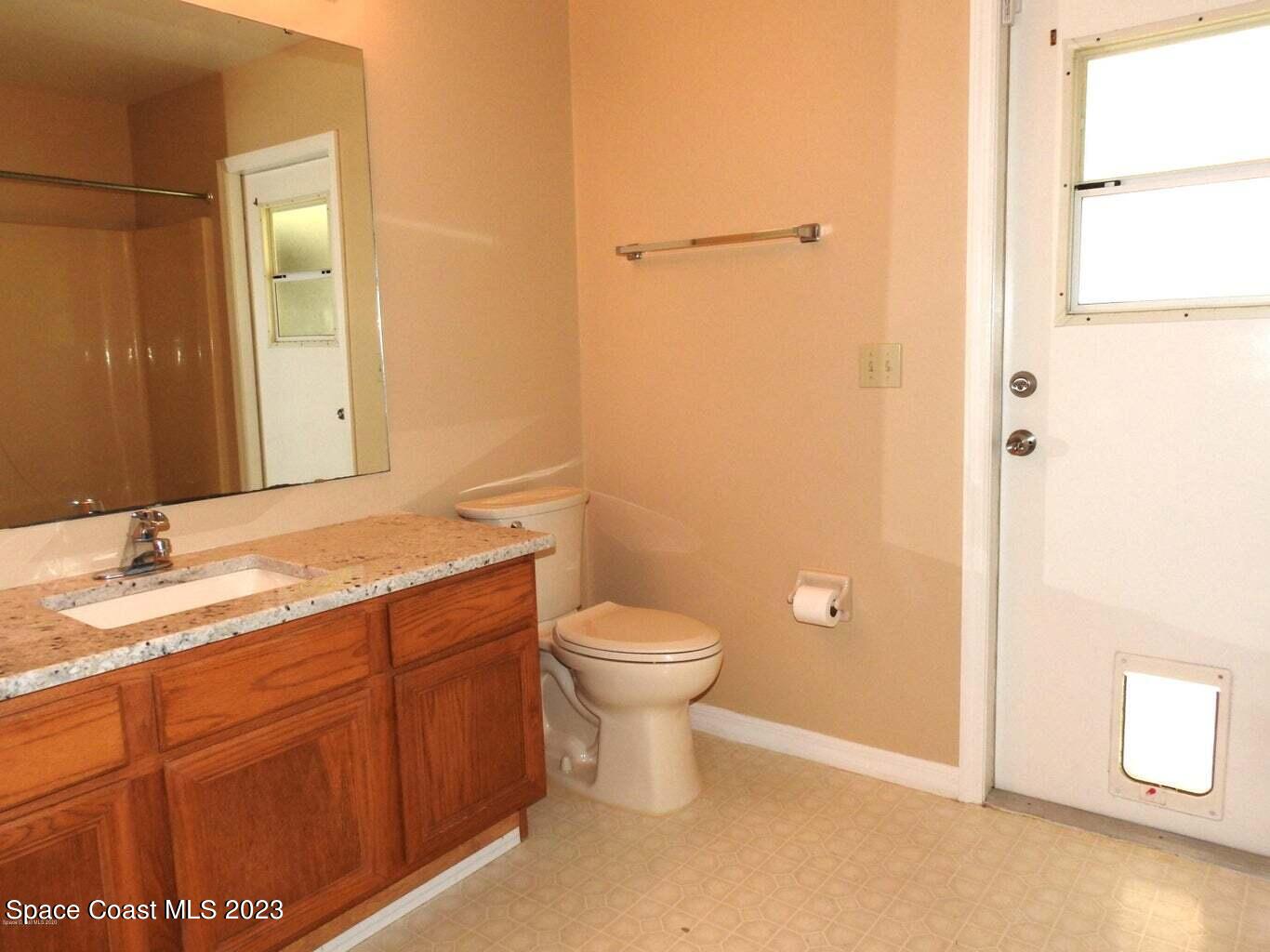 3368 Lakeview Circle Melbourne, FL 32934 - Photo 11 of 16 a bathroom with a granite countertop toilet a sink and a mirror