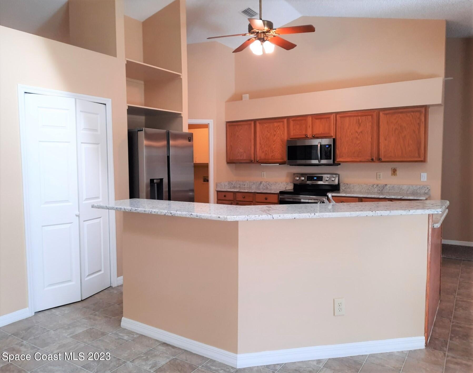 3368 Lakeview Circle Melbourne, FL 32934 - Photo 5 of 16 a kitchen with stainless steel appliances granite countertop a refrigerator a stove and a sink with wooden floor