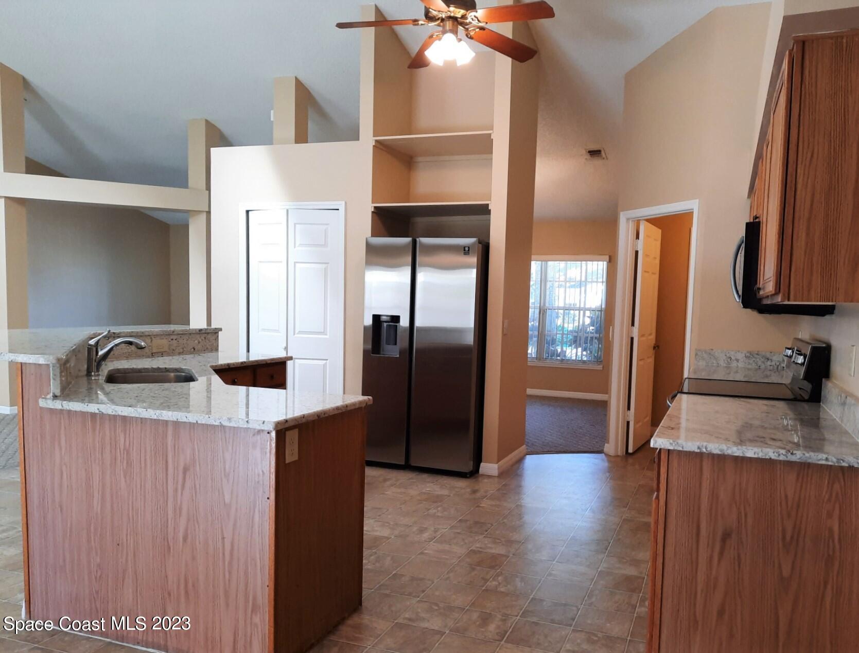 3368 Lakeview Circle Melbourne, FL 32934 - Photo 6 of 16 a kitchen with stainless steel appliances granite countertop a refrigerator a sink and a stove