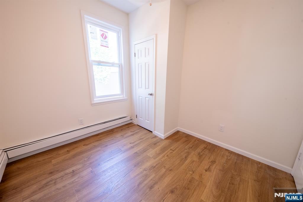 7723 Bergenline Avenue, Unit 3 North Bergen, NJ 07047 - Photo 12 of 12 an empty room with wooden floor and windows