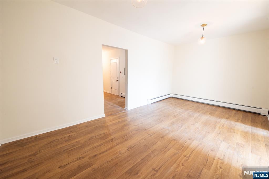 7723 Bergenline Avenue, Unit 3 North Bergen, NJ 07047 - Photo 5 of 12 an empty room with wooden floor and windows
