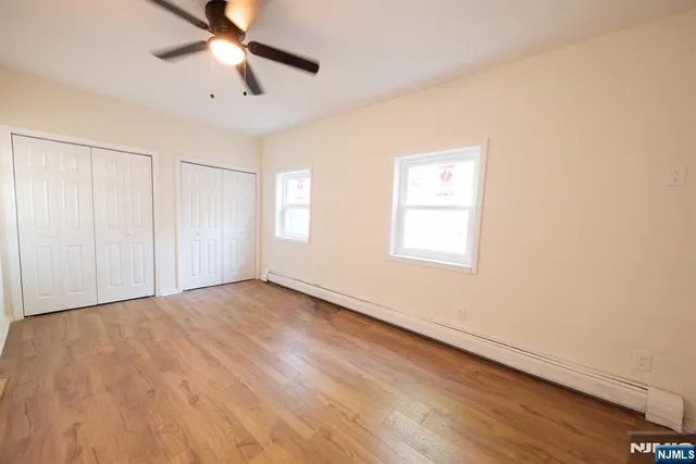 an empty room with wooden floor fan and windows