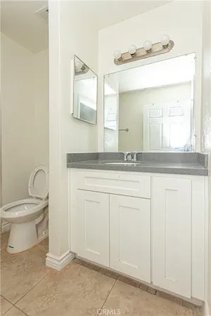 a bathroom with a granite countertop sink and a toilet