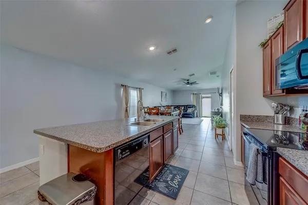 a large kitchen with stainless steel appliances a large counter top a stove and a sink