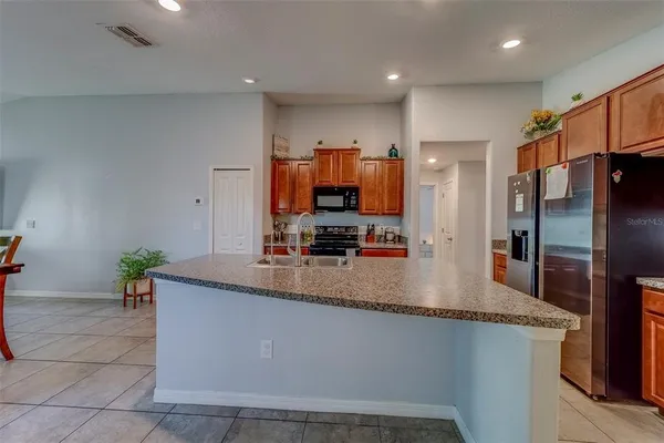 a kitchen with stainless steel appliances granite countertop a sink a refrigerator and a granite counter tops