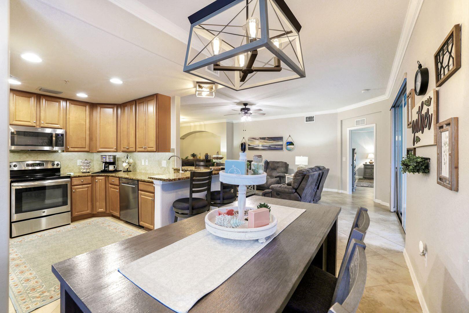 7878 Clemson Street, Unit 102 Naples, FL 34104 - Photo 4 of 20 a kitchen with a refrigerator a stove a sink dishwasher and a dining table with wooden floor