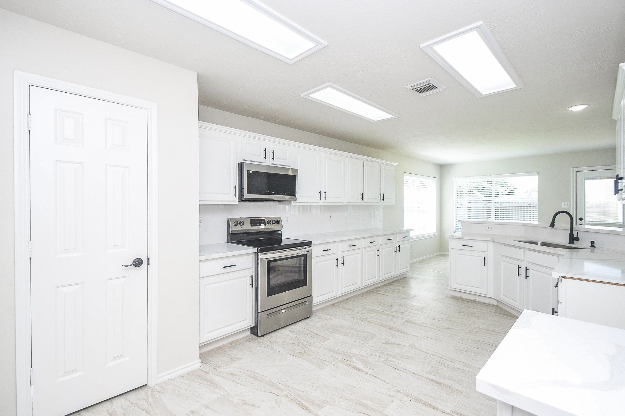 4810 Arbor Court Rosenberg, TX 77471 - Photo 4 of 20 a large white kitchen with stainless steel appliances granite countertop a stove top oven a sink dishwasher and white cabinets with wooden floor
