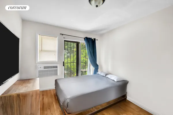 a bedroom with a bed and a flat tv screen on dresser