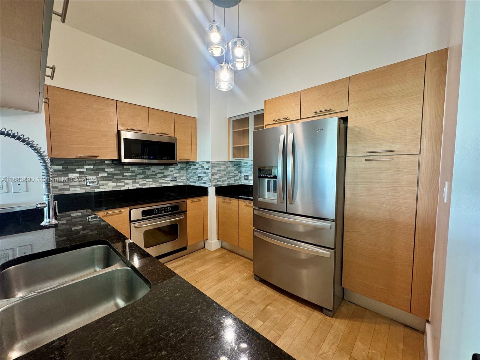 31 Southeast 5th Street, Unit 3817 Miami, FL 33131 - Photo 3 of 26 a kitchen with stainless steel appliances granite countertop a refrigerator a stove and a sink with wooden floor