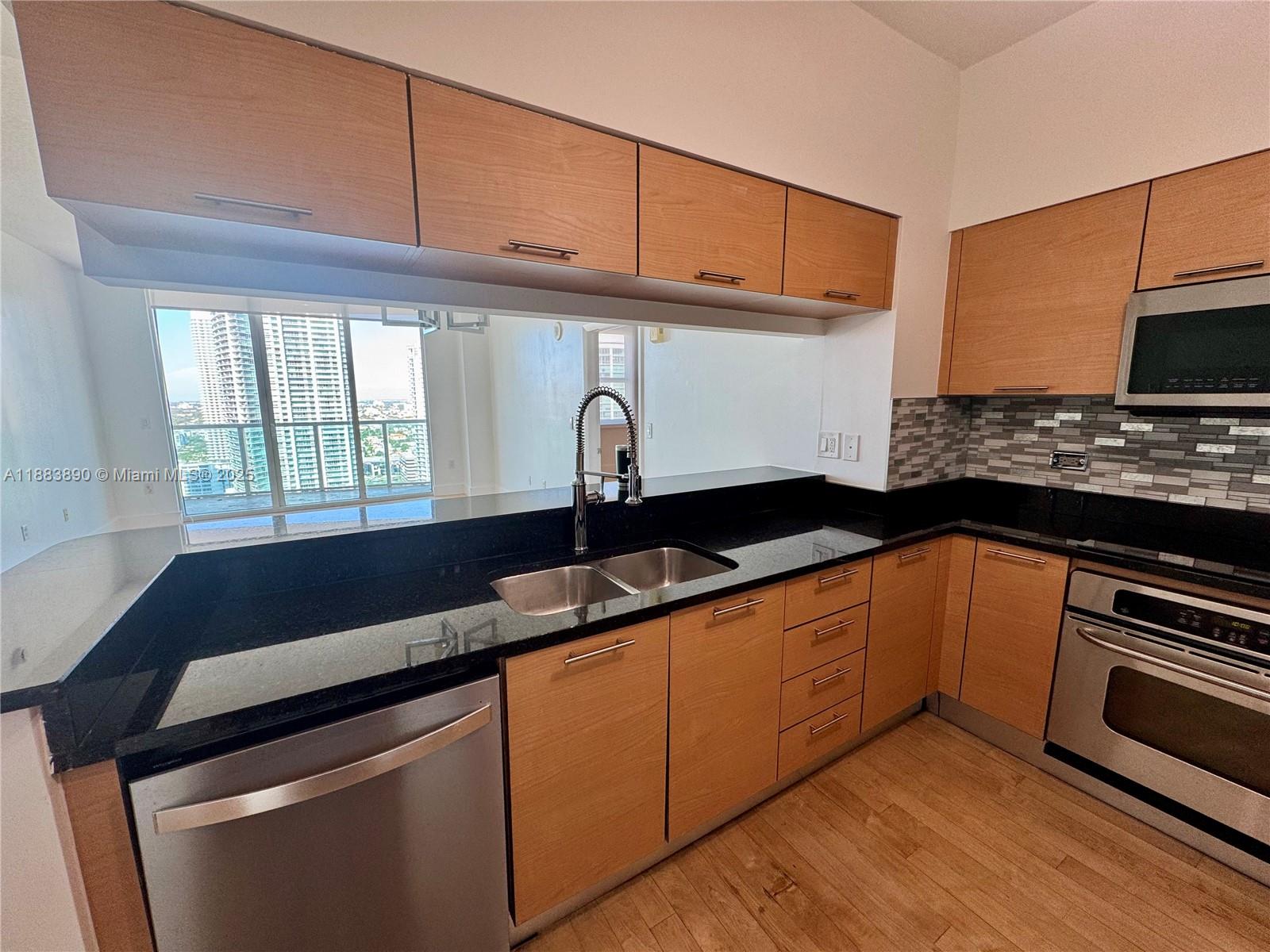 31 Southeast 5th Street, Unit 3817 Miami, FL 33131 - Photo 7 of 26 a kitchen with granite countertop a sink and a stove