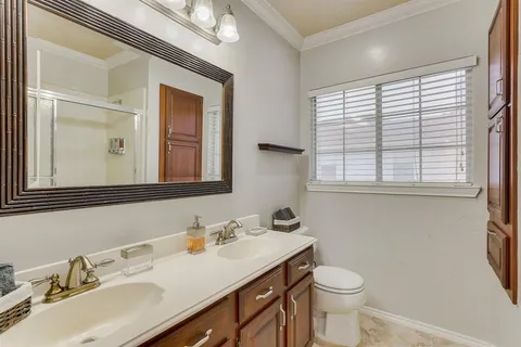 a bathroom with a granite countertop sink vanity mirror and toilet