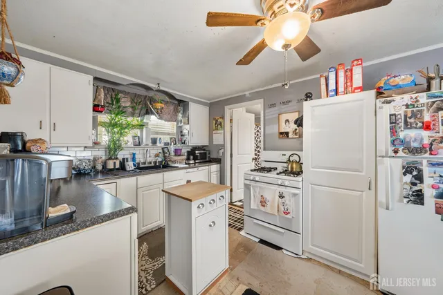 a kitchen with a refrigerator a stove cabinets dining table and chairs