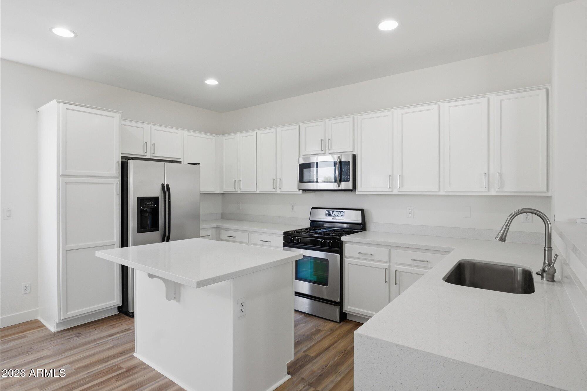 8838 West Payson Road Tolleson, AZ 85353 - Photo 4 of 22 a kitchen with a sink a stove a refrigerator and cabinets