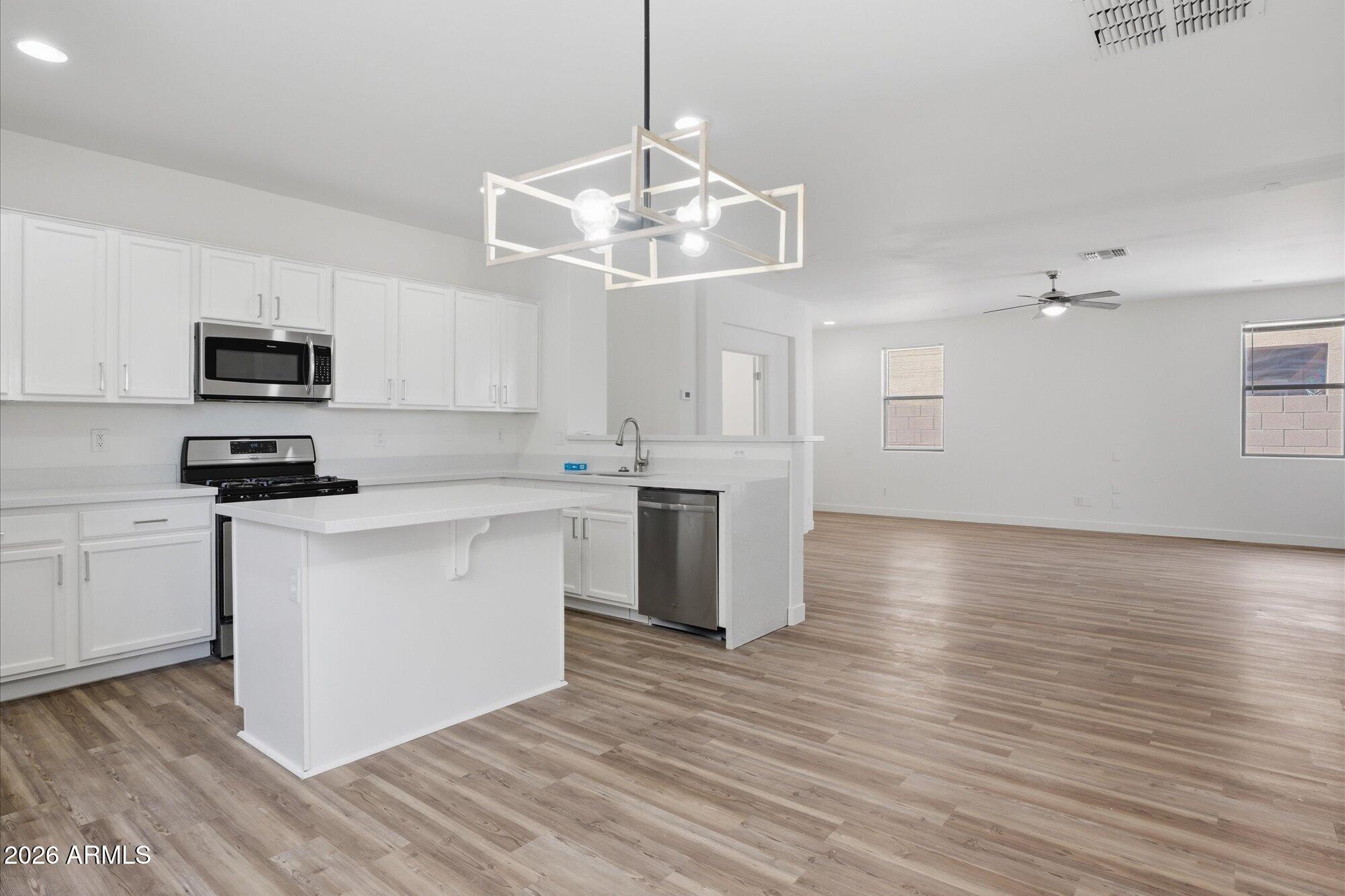 8838 West Payson Road Tolleson, AZ 85353 - Photo 5 of 22 a kitchen with stainless steel appliances a white stove top oven and a chandelier