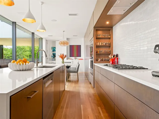 a kitchen with stainless steel appliances kitchen island granite countertop a sink cabinets and wooden floor
