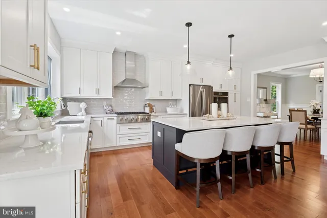 a kitchen with stainless steel appliances kitchen island granite countertop a table chairs and a wooden floor
