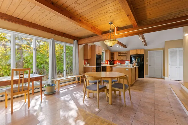 a dining hall with stainless steel appliances granite countertop a table and chairs with the view of living room