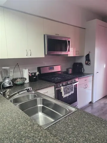 a kitchen with stainless steel appliances granite countertop a sink and a stove