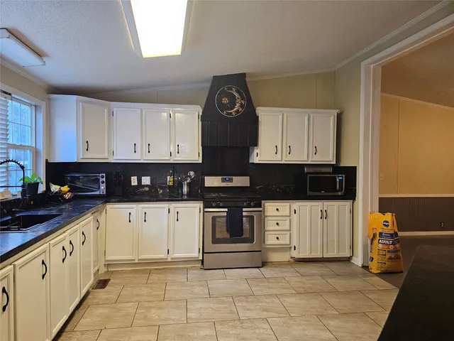 a kitchen with stainless steel appliances granite countertop a stove a sink and white cabinets