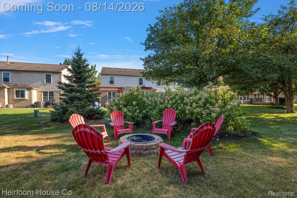 45697 Bryn Mawr Road Canton, MI 48187 - Photo 27 of 75 Expansive backyard featuring a stone-clad fire pit, mature deciduous trees, evergreen trees, and manicured lawn