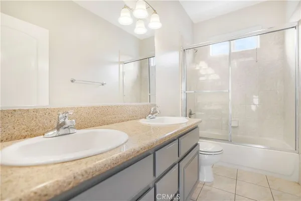 a bathroom with a granite countertop sink a toilet a mirror and shower