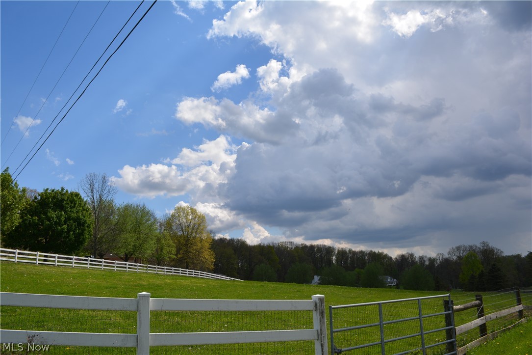 2363 Tabor Ridge Road Northeast New Philadelphia, OH 44663 - Photo 18 of 42 Expansive green pasture with a white multi-rail fence and a metal gate
