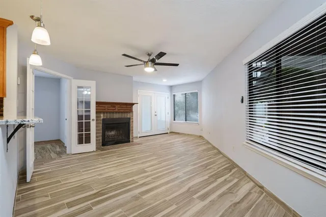 a view of a livingroom with a fireplace a ceiling fan and windows