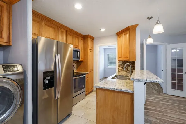 a kitchen with stainless steel appliances granite countertop a refrigerator a stove and a sink