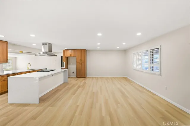 a large kitchen with stainless steel appliances a large counter top a stove and a refrigerator